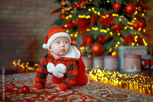 Little six month old baby dressed as Santa Claus. Background for christmas card. The child looks down at the place for inscription.