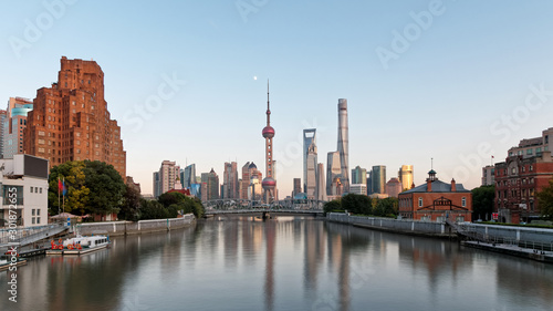 beautiful shanghai bund viewed from suzhou river in evening with moon and blue sky background, including many famous landmarks in Shanghai. © atiger