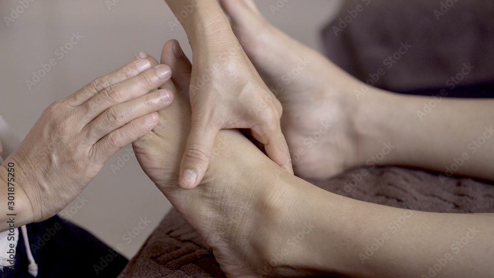 Woman very relaxing with foot massage procedure in spa salon during treatment