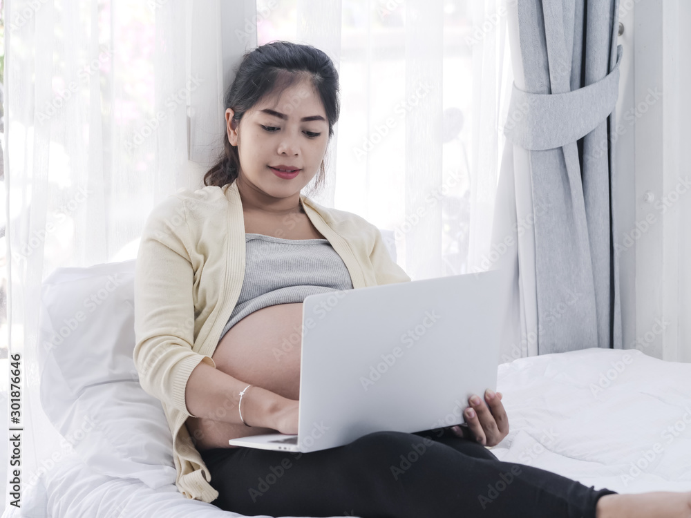 Asian pregnant woman using laptop on bed at home, lifestyle concept. Asian pregnant woman using laptop on bed at home, lifestyle concept.