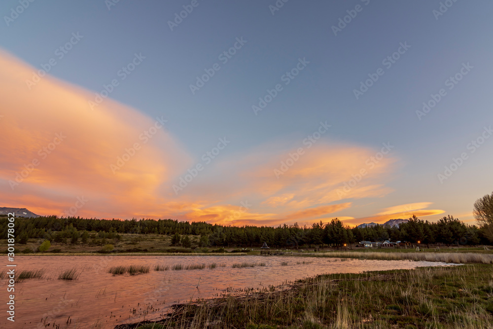 Panoramic view of lake and Andes mountains beneath lenticular clouds during sunset in Esquel, Patagonia, Argentina
