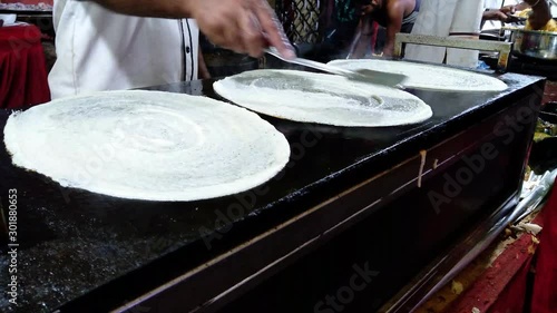 Chef making three dosa in a row. Dosa Indian food chef hand while cooking Dosa.