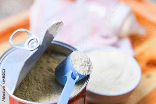 Milk powder in spoon on can and wooden table baby milk bottle