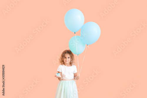 Little girl with balloons and gift on color background