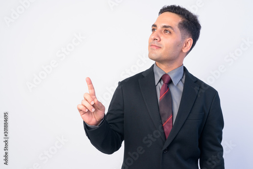 Portrait of handsome Persian businessman in suit thinking and pointing up