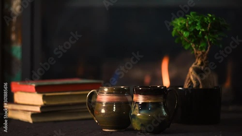 Two potteruy mugs with a fireplace in the background