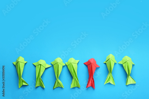 Принти на полотні Red origami fish among green ones on color background