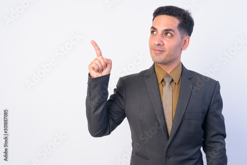 Portrait of handsome Persian businessman in suit thinking while pointing up