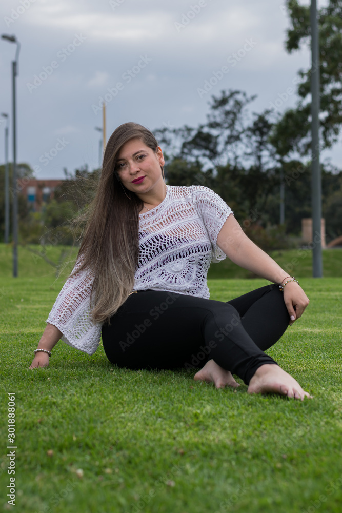 LATIN WOMAN WITH BLACK PANTS SITTING ON THE LAWN LATIN WOMAN WITH BLACK PANTS SITTING ON THE LAWN