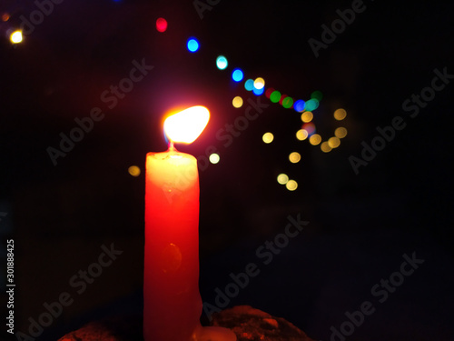 A CANDLE FLAME GIVE LIGHT IN DARK NIGHT WITH LIGHT BILINKING BEHIND