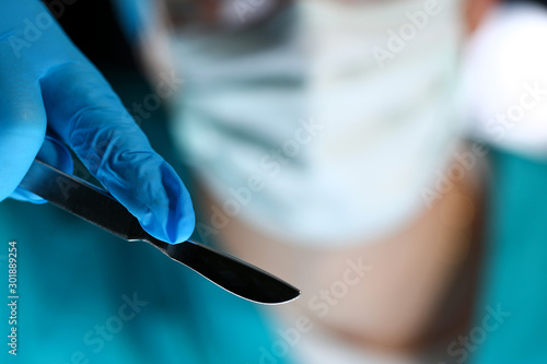 Stampa su tela Surgeon arms in sterile uniform holding sharp knife