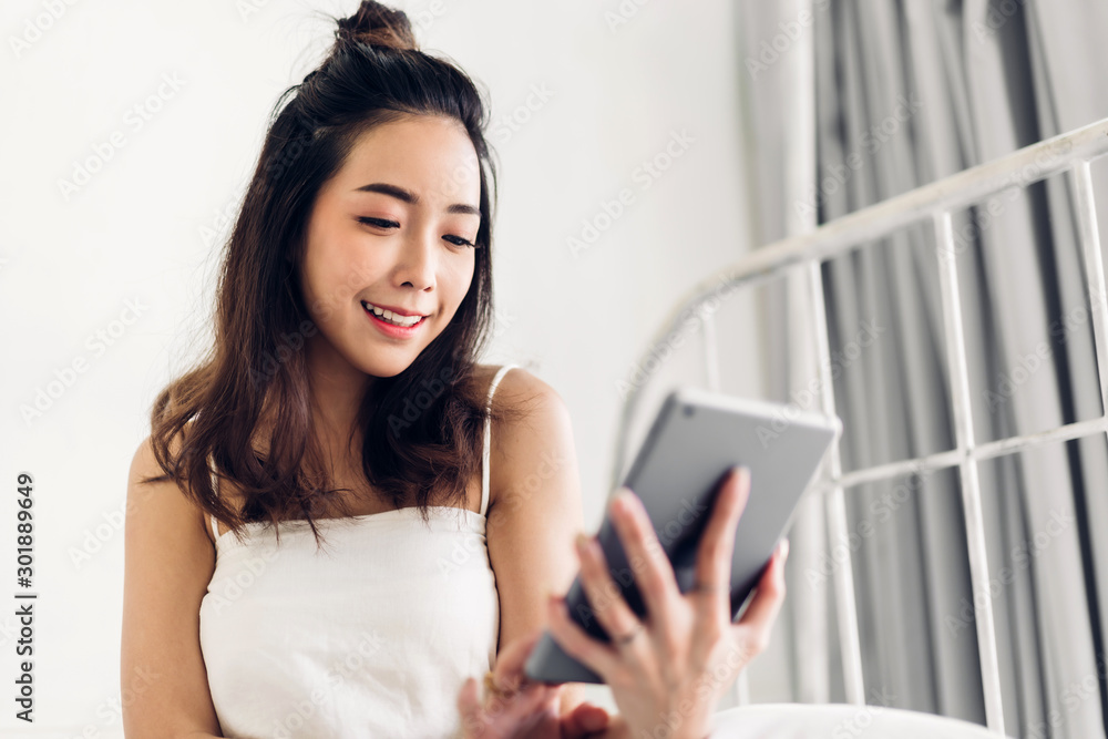 Happy woman relaxing using tablet computer on the bed at home.technology and communication concept Happy woman relaxing using tablet computer on the bed at home.technology and communication concept