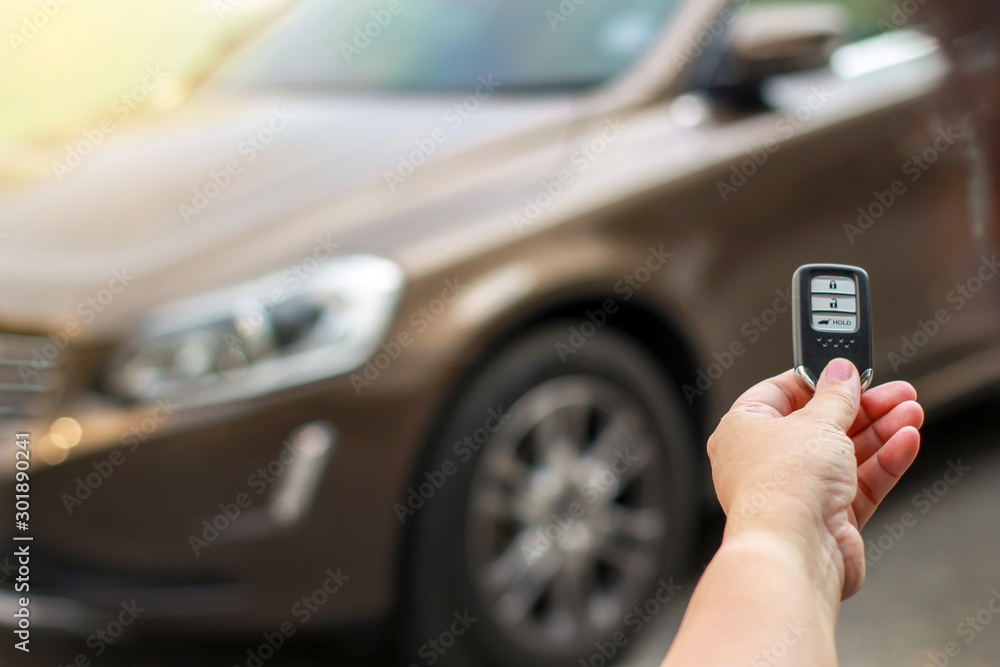 Human hand holding the car remote control against blur car. Human hand holding the car remote control against blur car.