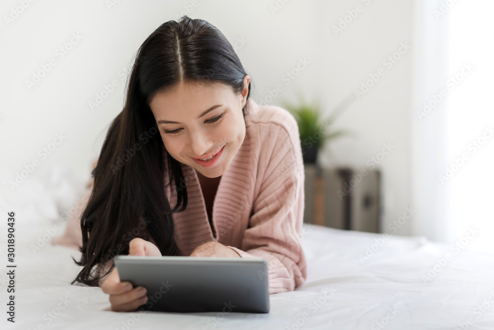 Woman relaxing and using digital tablet computer on the bed at home.woman checking social apps and working.Communication and technology concept Woman relaxing and using digital tablet computer on the bed at home.woman checking social apps and working.Communication and technology concept