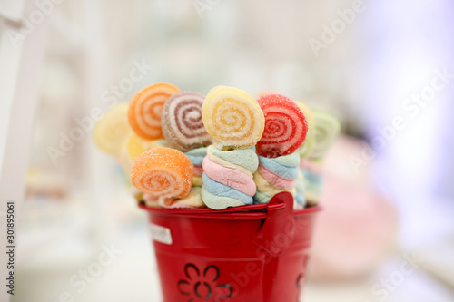 Colorful candy with sticks closeup rainbow on red pot