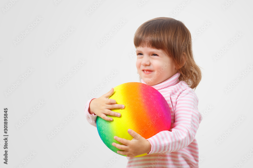 Adoption and parenting by homosexual couple and families concept. Children against homophobia.Sweet two year old little baby girl with a happy face smiles and hugs a large ball painted LGBT rainbow. Adoption and parenting by homosexual couple and families concept. Children against homophobia.Sweet two year old little baby girl with a happy face smiles and hugs a large ball painted LGBT rainbow.