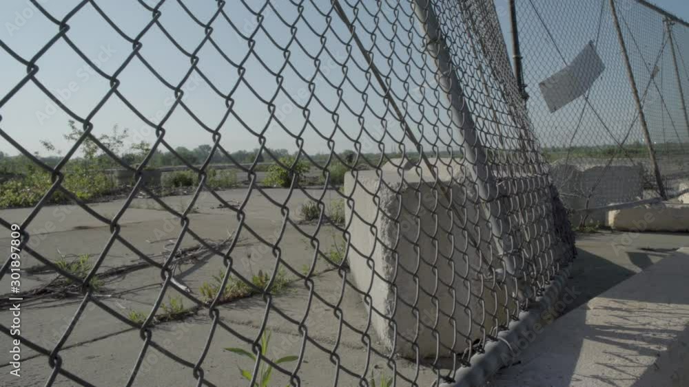 An old rusty chain-link fence bars entrance to a deserted industrial lot left over from GM manufacturing days in Flint, Michigan. An old rusty chain-link fence bars entrance to a deserted industrial lot left over from GM manufacturing days in Flint, Michigan.