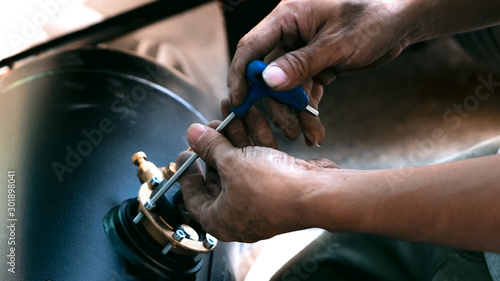 The technician is using a screwdriver to adjust the position of the pressure gauge valve,reiterate the valve.