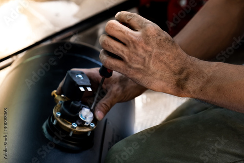 The technician is using a screwdriver to adjust the position of the pressure gauge valve,reiterate the valve.