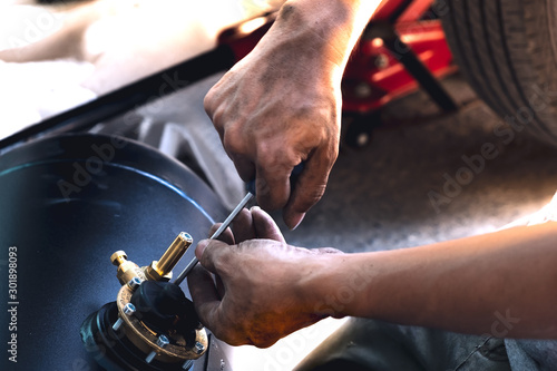 The technician is using a screwdriver to adjust the position of the pressure gauge valve,reiterate the valve.