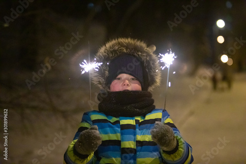 little boy at night winter city park in warm coat with sparkler © phpetrunina14
