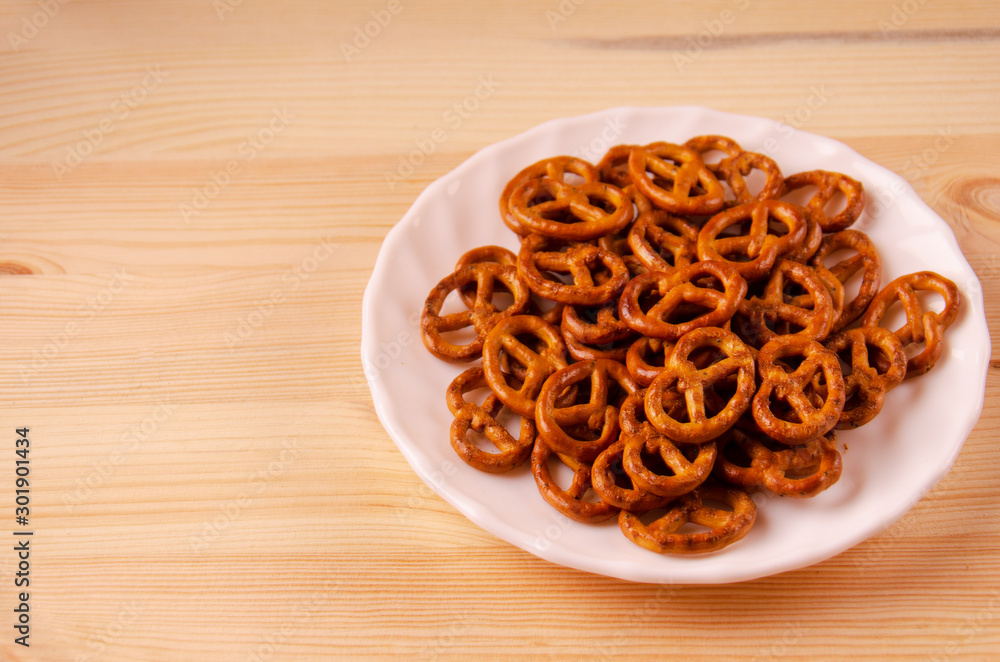 Curly cookies on a white plate. Wooden surface. Curly cookies on a white plate. Wooden surface.