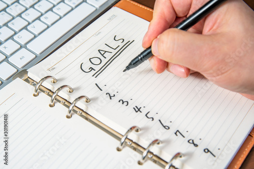 Close-up of a businessman's hand writing goals and list in the diary.
