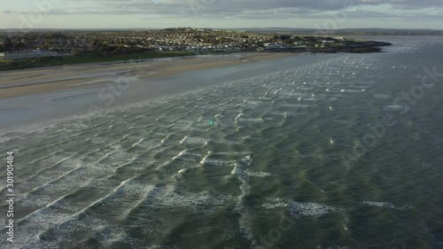 Kite surfer close to the beach, riding the wind with his kite, Drone footage. Aerial footage from high angle on a kite surfer.