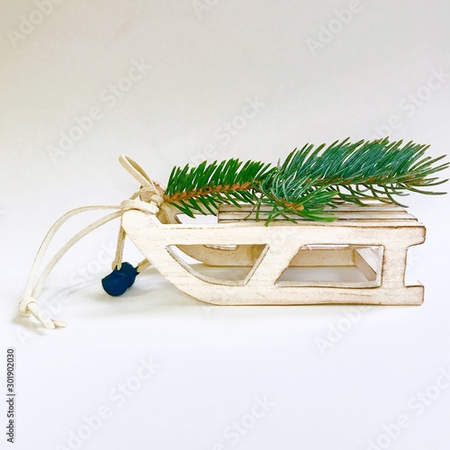 White wooden toy sled with christmas tree branch isolated on white