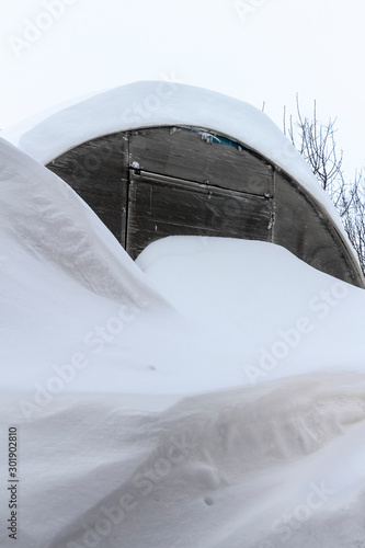 The greenhouse in the backyard was covered with snow.