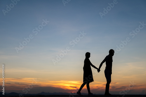 Silhouettes of happy young couple against the sunset sky.