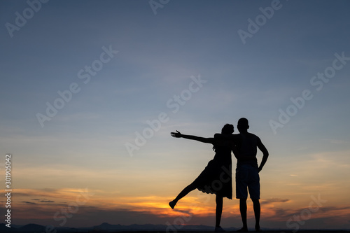 Silhouettes of happy young couple against the sunset sky. © max_play