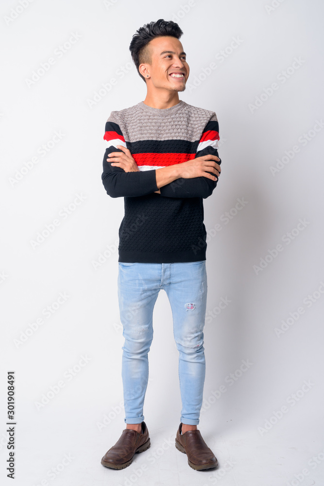 Full body shot of happy young Asian man thinking with arms crossed Full body shot of happy young Asian man thinking with arms crossed
