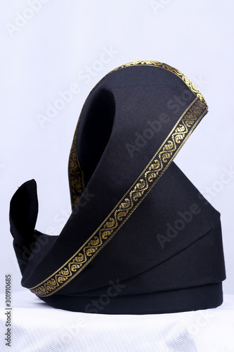 A Malay black coloured with gold lace traditional "tengkolok/destar/tanjak".