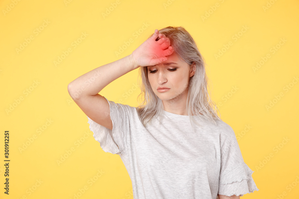 Sad stressed young woman feelin headache standing in the yellow studio