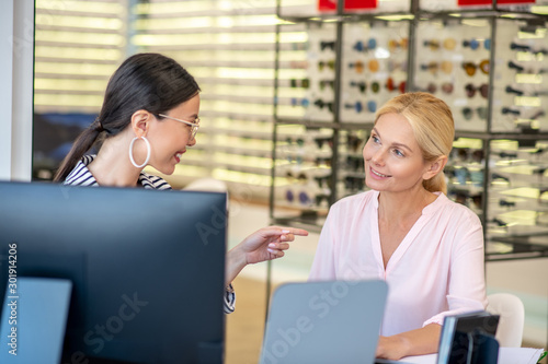 Dark-haired trainee smiling while showing her work results photo