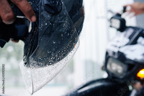 Close-up image of wet helmet glass with drops of water in hands of motorcyclist © DragonImages
