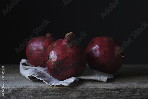 Fotografija Still life photography shot of three gorgeous pomegranates on a wooden deck