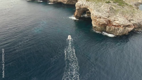 Boat Headed Toward The Alcaufar Defense Tower In Menorca, Morro d'Alcaufar, Spain On A Sunny Day - Aerial Shot photo