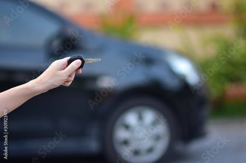 Salesman holding Key of car and car parked background