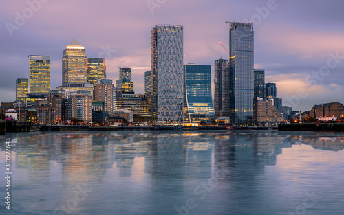 Canary wharf cityscape. The buildings are reflected in Thames river’s water. Canary wharf is the business districet in London City UK. Wihtout company logos © GezaKurkaPhotos