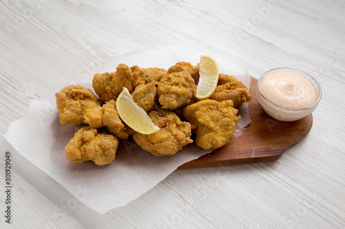Homemade crispy japanese fried chicken Karaage on a rustic wooden board over white wooden surface, side view. Closeup.