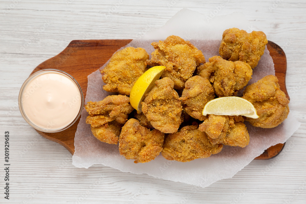 Homemade traditional japanese fried chicken Karaage on a rustic wooden board over white wooden background, top view. Flat lay, overhead, from above. Homemade traditional japanese fried chicken Karaage on a rustic wooden board over white wooden background, top view. Flat lay, overhead, from above.