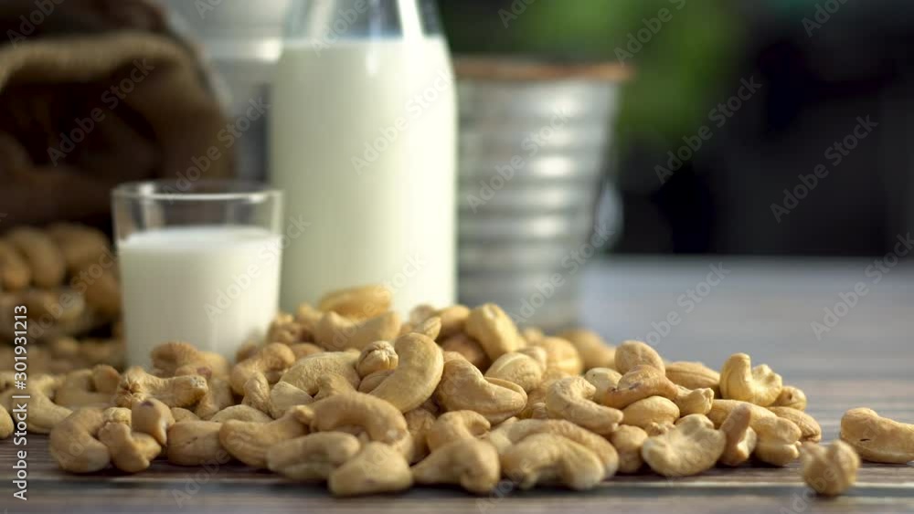 Still life of cashew milk and toasted cashew nuts on table, Shot in studio, movement camera, selective focus and free space for text. Good healthy food ideas concept. Still life of cashew milk and toasted cashew nuts on table, Shot in studio, movement camera, selective focus and free space for text. Good healthy food ideas concept.