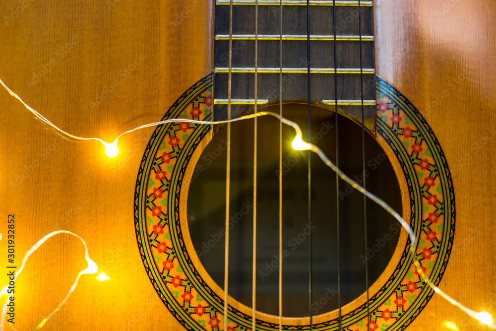 Obraz premium acoustic guitar wrapped in a luminous garland. Christmas gift
