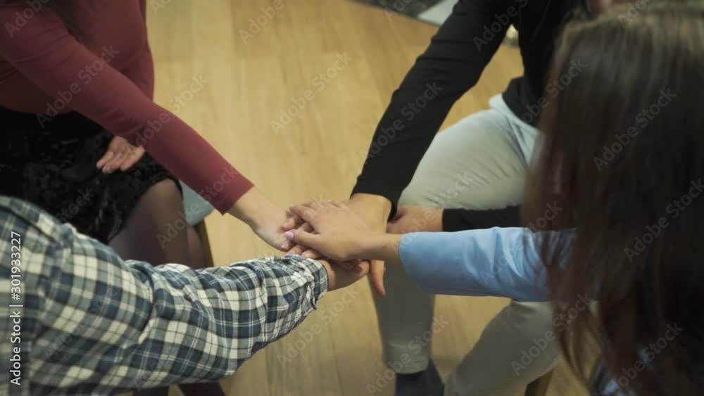 Close-up of four Caucasian hands putted on top of each other. People sitting in circle with friends. Group therapy, psychological treatment, empathy, unity. Close-up of four Caucasian hands putted on top of each other. People sitting in circle with friends. Group therapy, psychological treatment, empathy, unity.