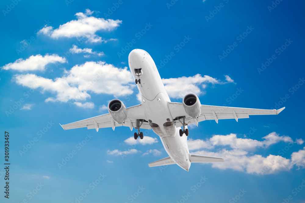 Obraz premium white passenger plane has released its landing gear and is coming in to land with background of white clouds and blue sky