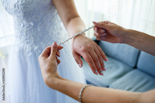 bride puts on wedding jewelry on the wedding day