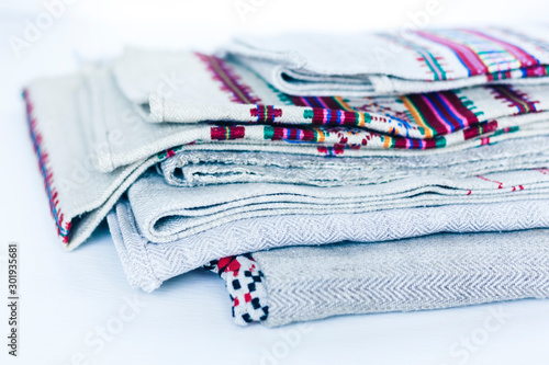 A stack of woven linen towels with embroidery, traditional handmade in Ukraine.