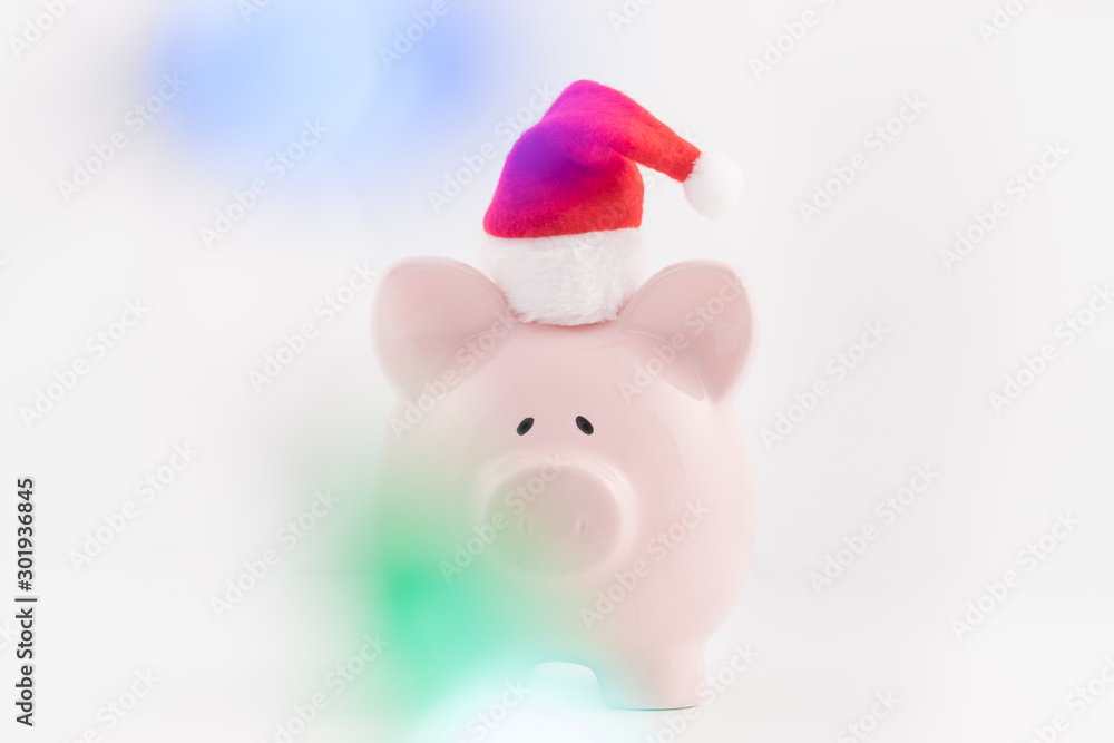 Concept image for savings planning featuring a pink piggy bank wearing a red Santa hat. Concept image for savings planning featuring a pink piggy bank wearing a red Santa hat.